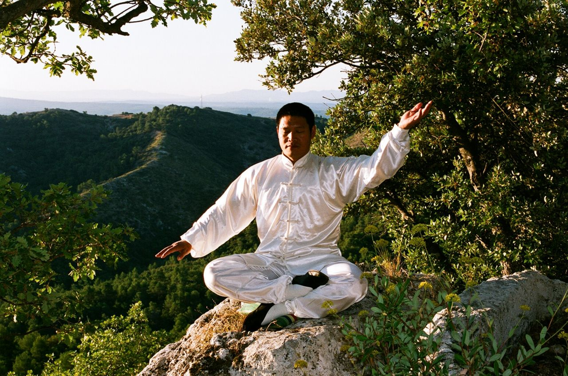 Shifu Liu practising tai chi on a mountain at sunset